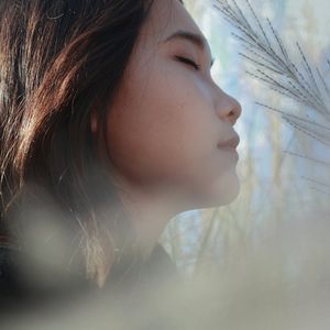 A calm person taking a deep breath with closed eyes.